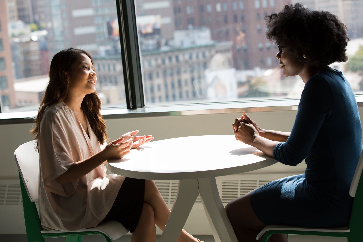 Dos compañeras conversando con calma junto a una ventana