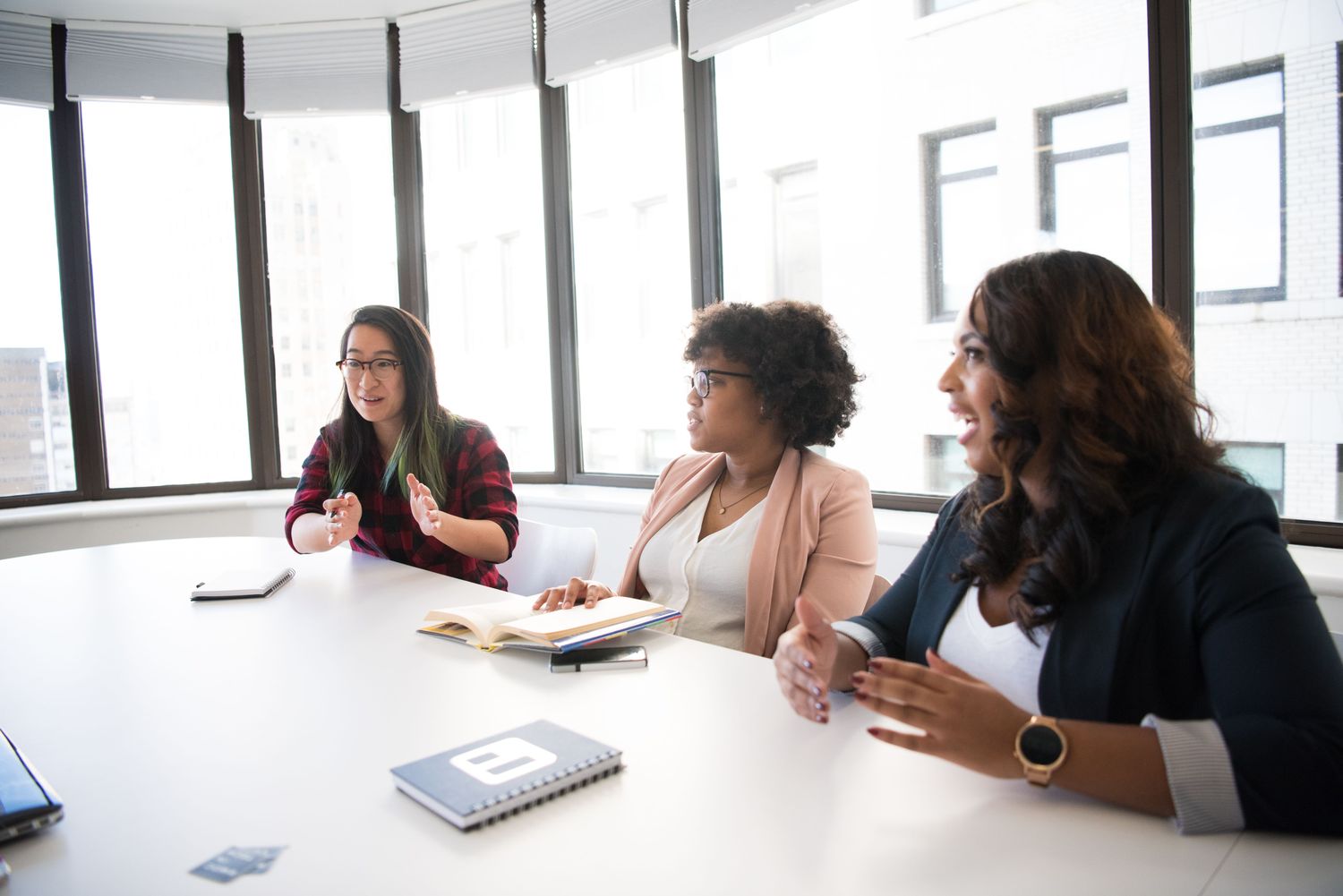 Tres compañeras conversando en una reunión de equipo