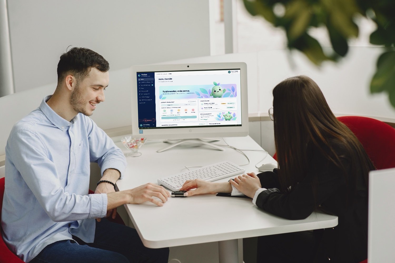 Dos personas conversando frente a un computador con el portal de colaboradores de Tictiva en pantalla