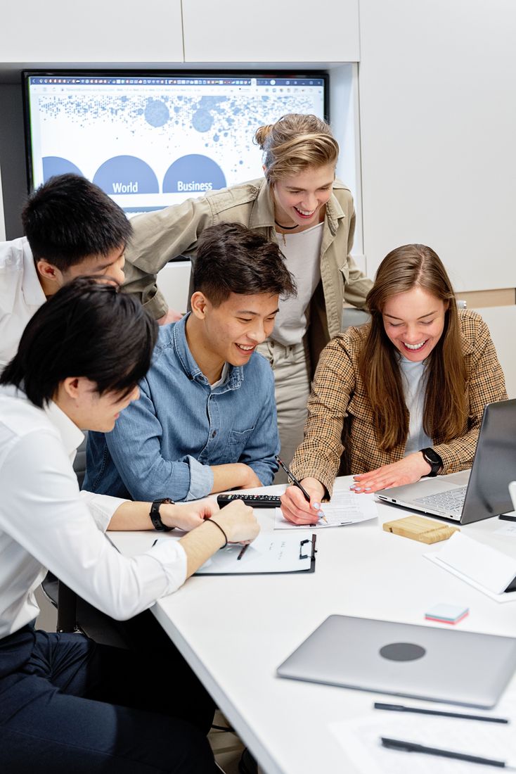 Equipo diverso riendo y trabajando junto alrededor de una mesa