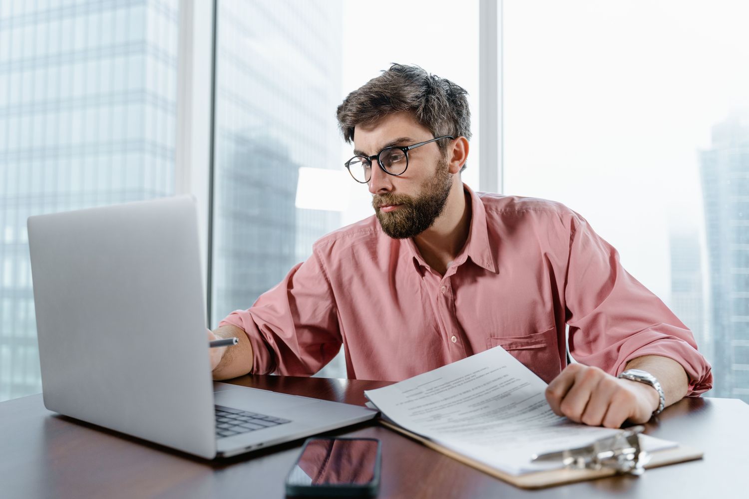 Profesional revisando documentos y su computador con concentración